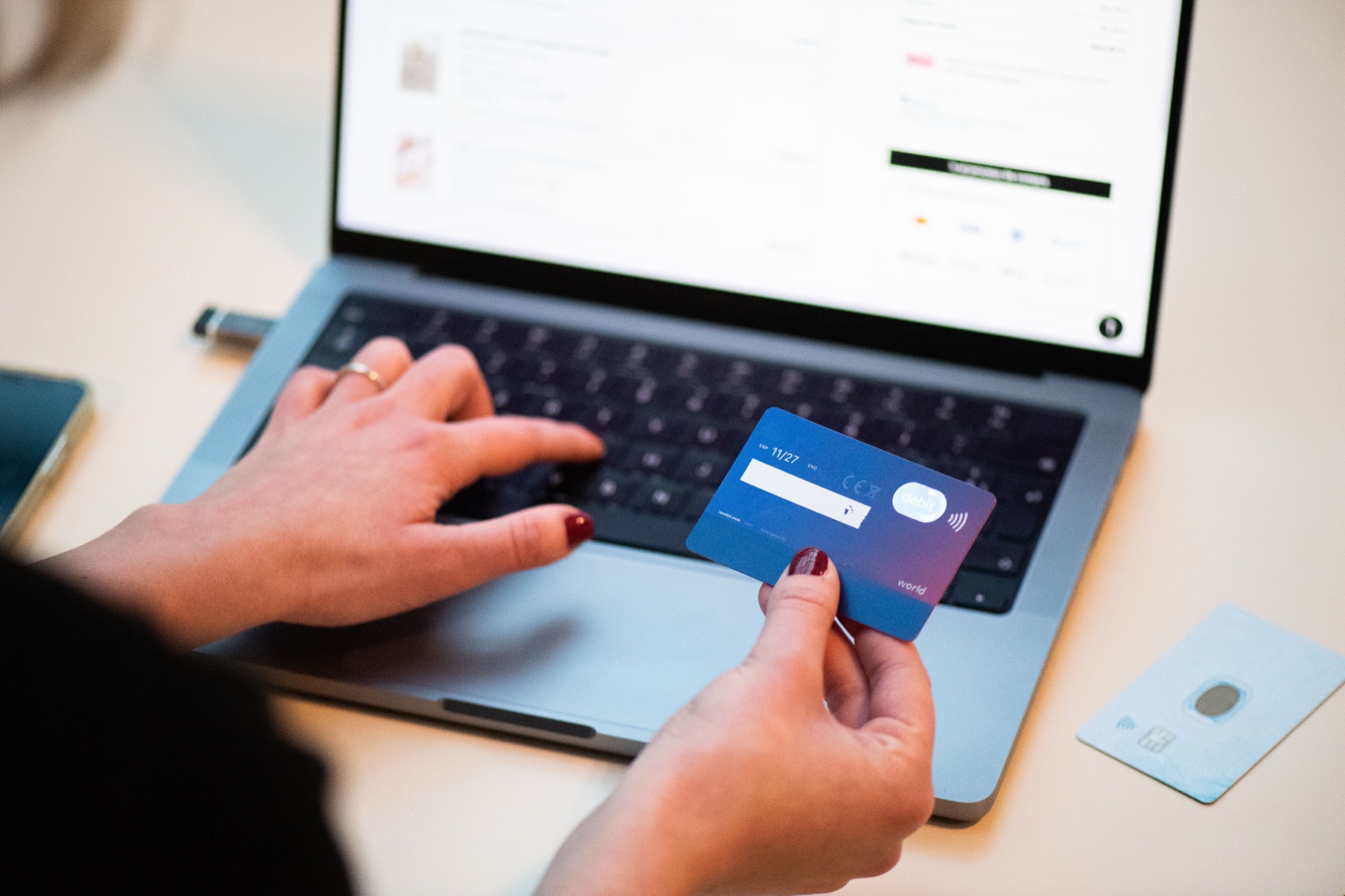 Une personne règle un achat en ligne avec une carte bancaire, devant un ordinateur portable